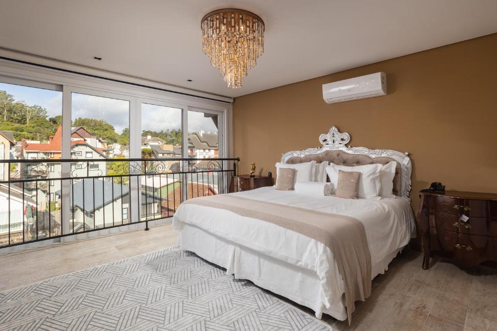 Quarto do Hotel Fioreze Centro, em Gramado, com cama de casal, cabeceira prateada e janelas voltadas para a cidade