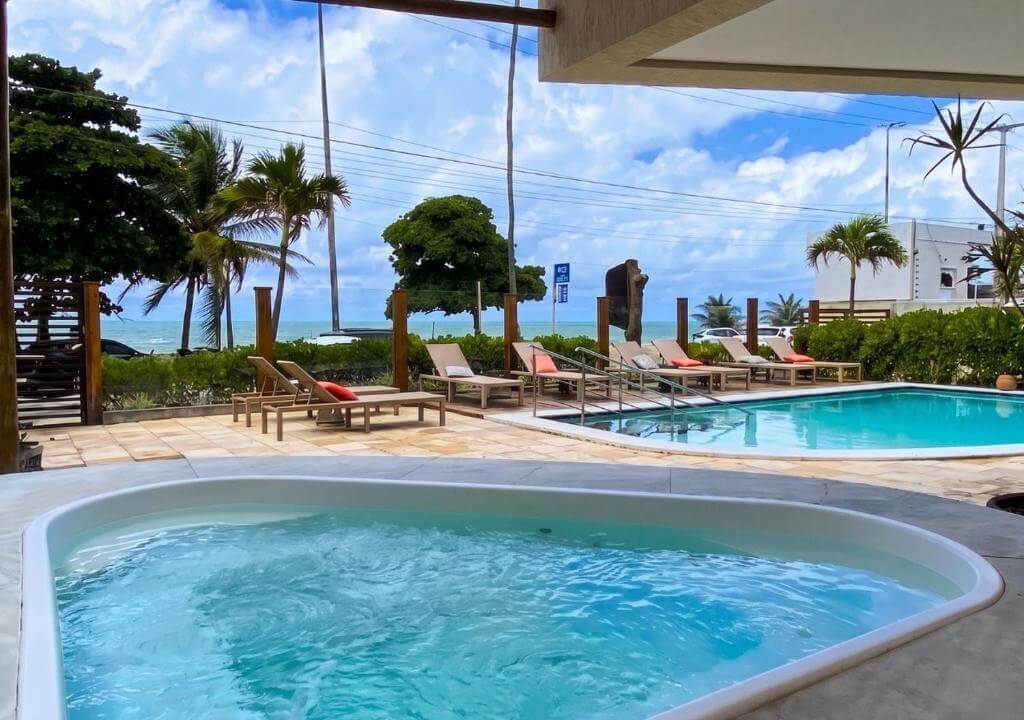 Área da piscina do Kastel Jampa Hotel, em João Pessoa, com hidromassagem, espreguiçadeiras e vista para o mar
