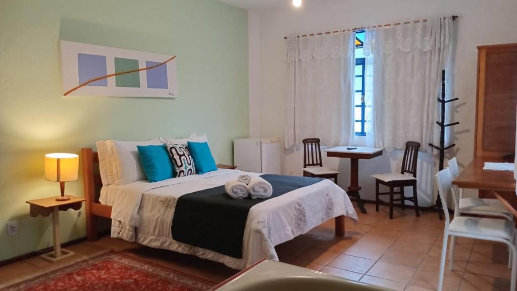Suíte da Pousada 3 Corações Penedo com cama de casal e área de estar.