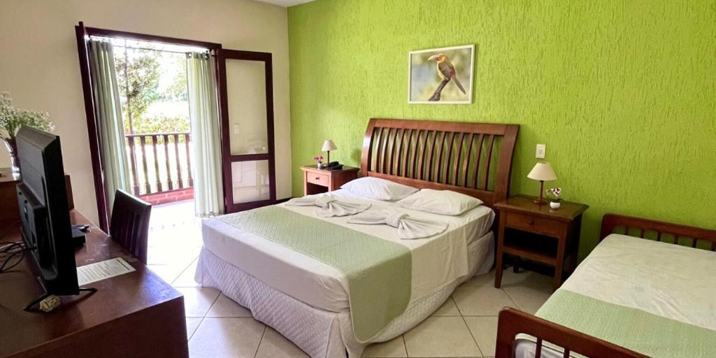 Quarto da Pousada Finlândia em Penedo com cama de casal, cama de solteiro e varanda.