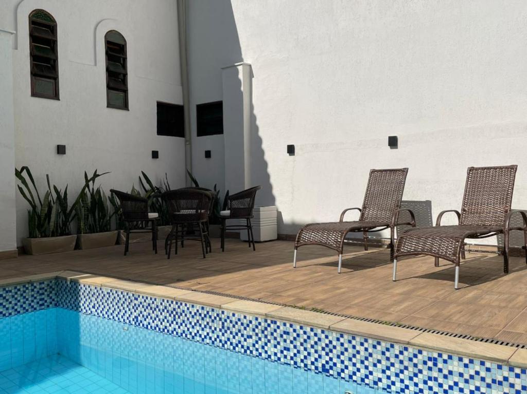 Área da piscina da Pousada Finlândia em Penedo com espreguiçadeiras e mesas externas.