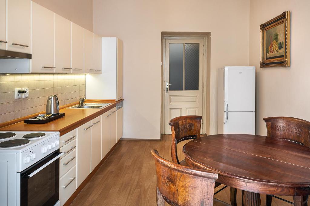 Cozinha do BHG Apartments, em Praga, com armários claros, mesa redonda de madeira e geladeira branca