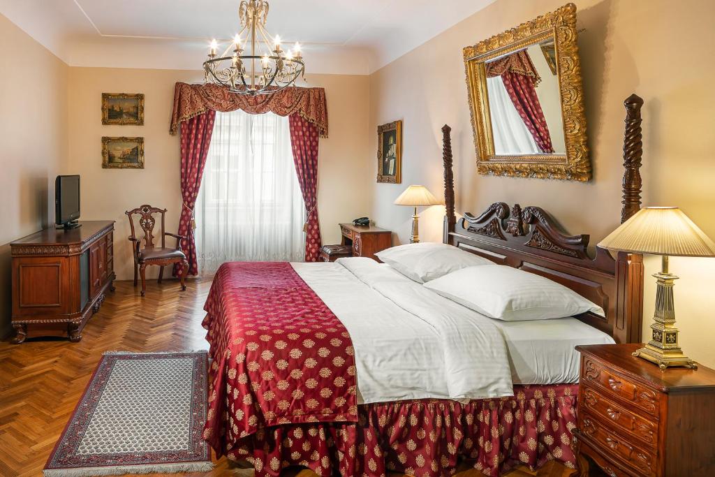 Quarto do BHG Apartments, em Praga, com cama de madeira entalhada, roupa de cama vermelha e lustre metálico