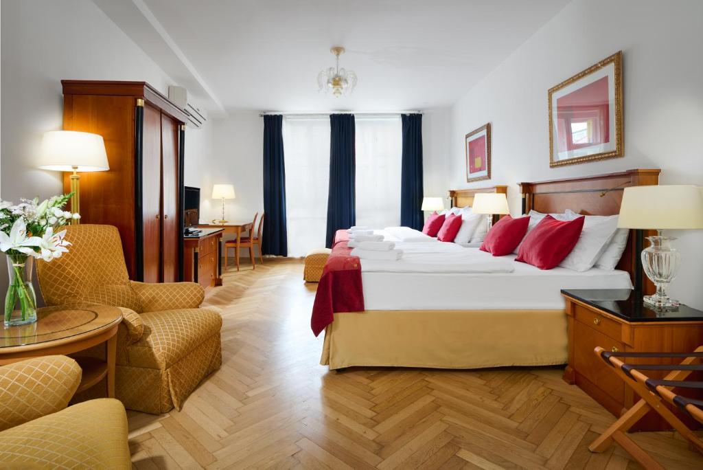Quarto do Hotel Leon D’Oro, em Praga, com duas camas, almofadas vermelhas e móveis de madeira