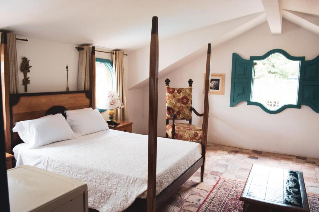 Quarto da Pousada Richard Rothe em Tiradentes com cama de dossel e decoração colonial.