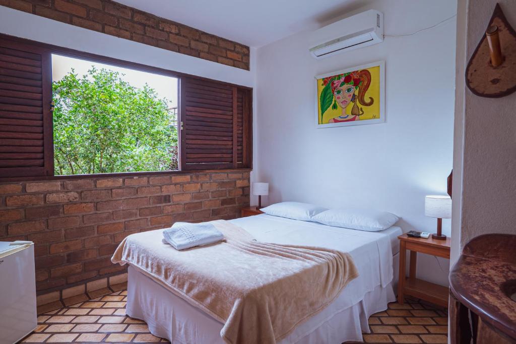 Quarto da Pousada Alto do Cajueiro na Chapada Diamantina com janela ampla voltada para a natureza.