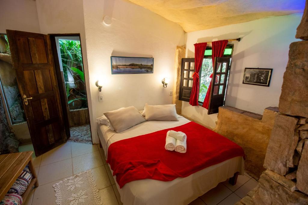 Quarto da Pousada Flor de Açucena na Chapada Diamantina com decoração rústica e detalhes vermelhos.