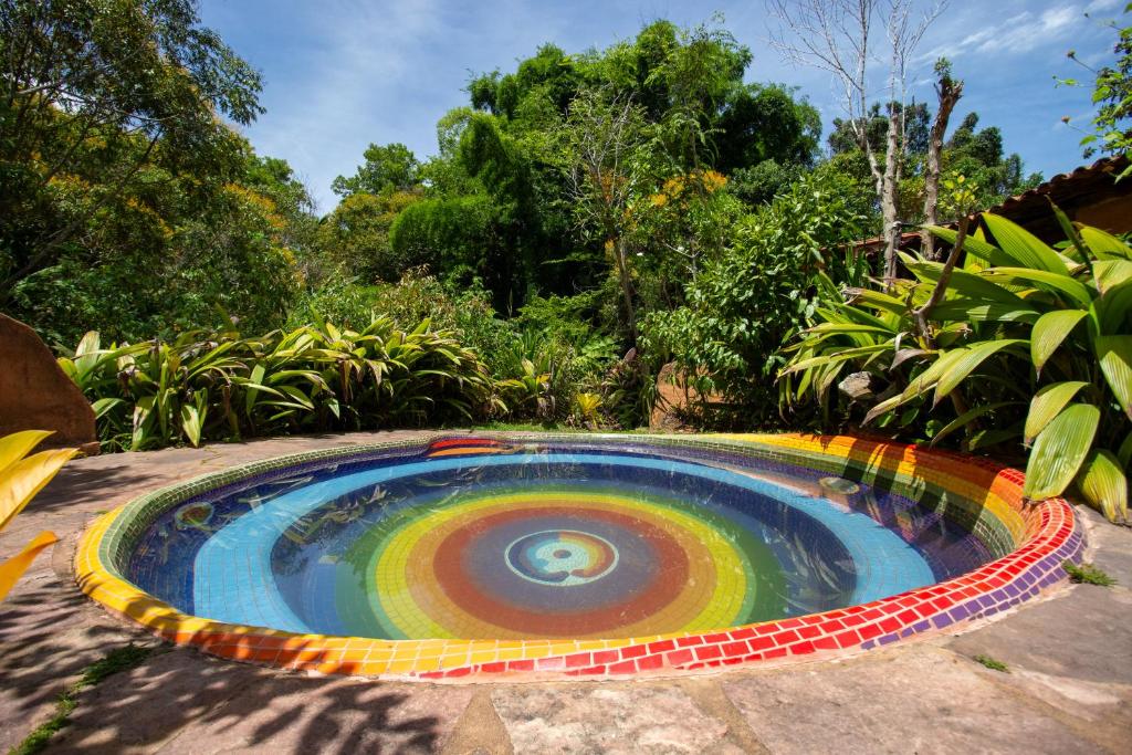 Piscina circular colorida da Pousada Flor de Açucena na Chapada Diamantina cercada por jardim tropical.