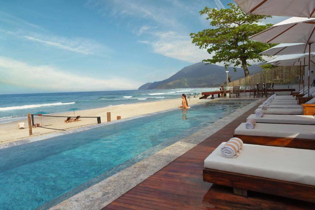 Área da piscina do Duke Beach Hotel Maresias, com borda infinita de frente para a praia