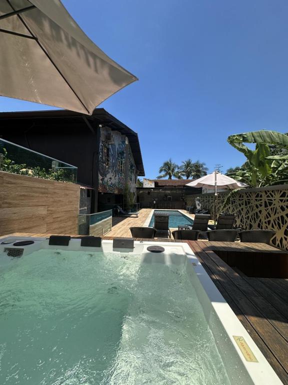 Área externa do Hotel La Serena, em Maresias, com hidromassagem, piscina e deck com espreguiçadeiras