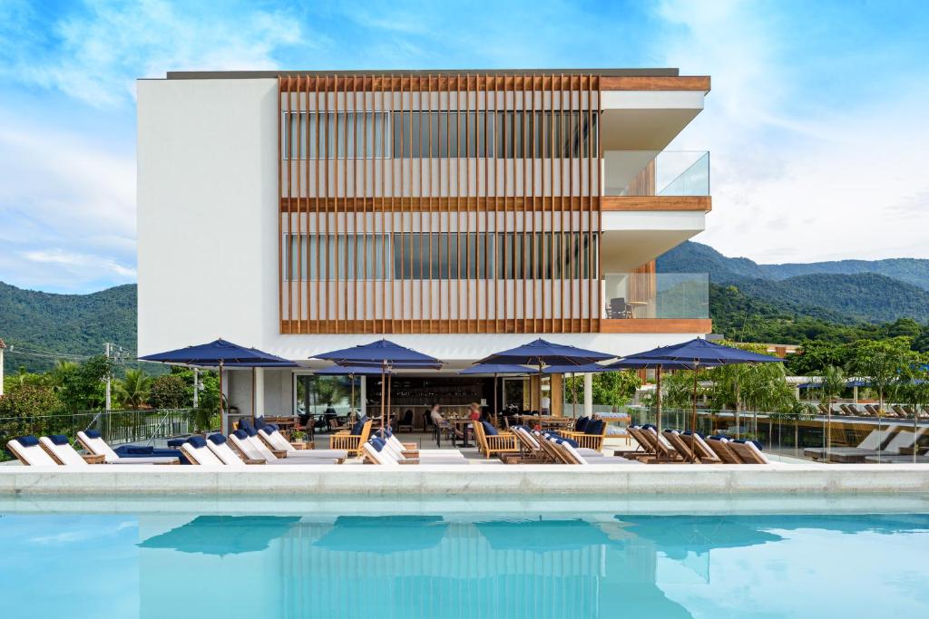 Fachada do Hotel Fasano Angra dos Reis, com piscina, espreguiçadeiras e montanhas ao fundo