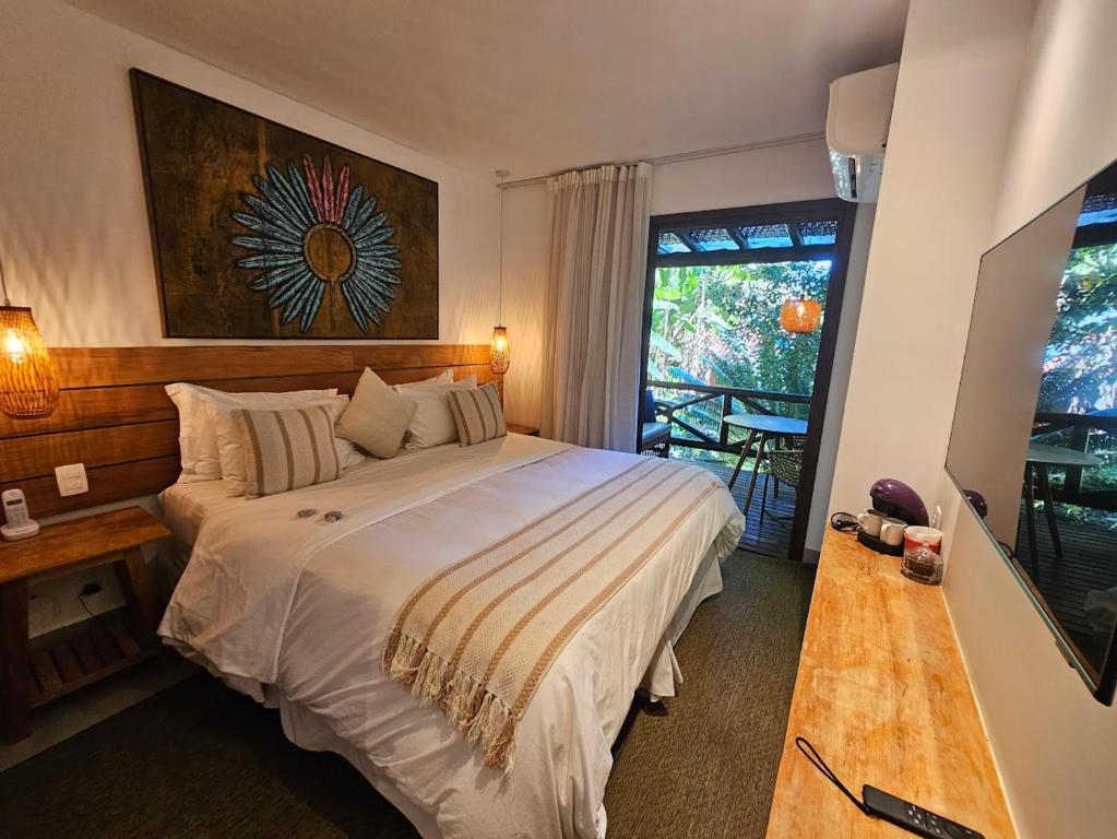 Quarto da Pousada e Mergulho Jamanta, com cama de casal e varanda voltada para a vegetação