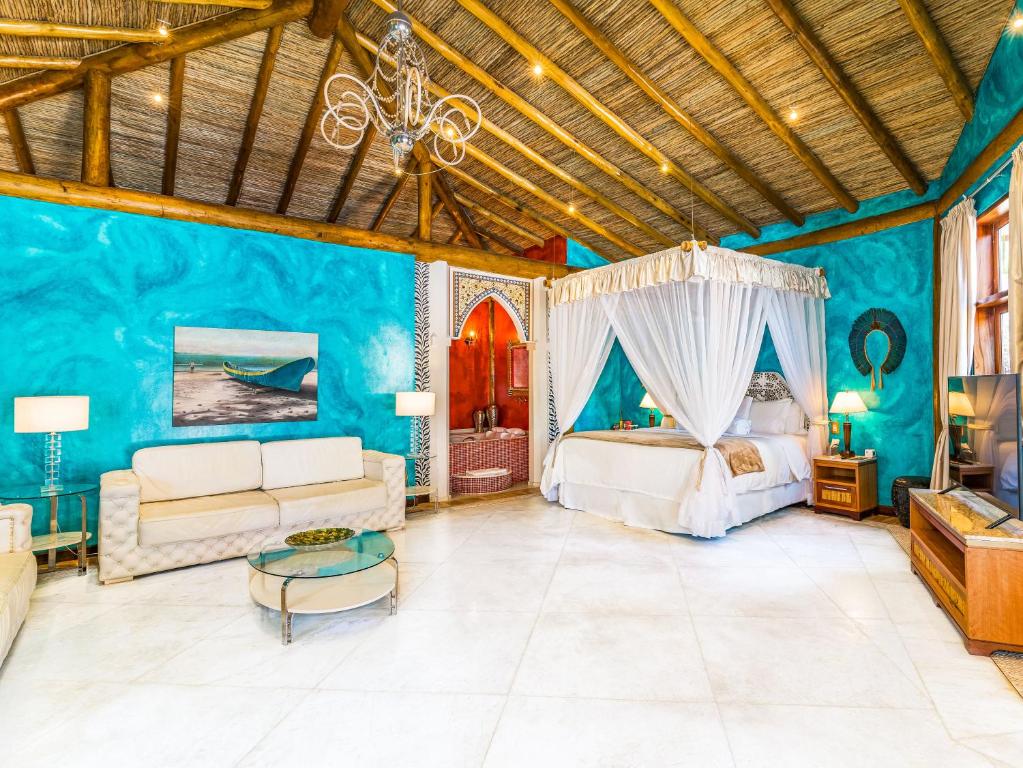 Suíte do DPNY Beach Hotel & Spa Ilhabela, com cama de dossel e paredes turquesa