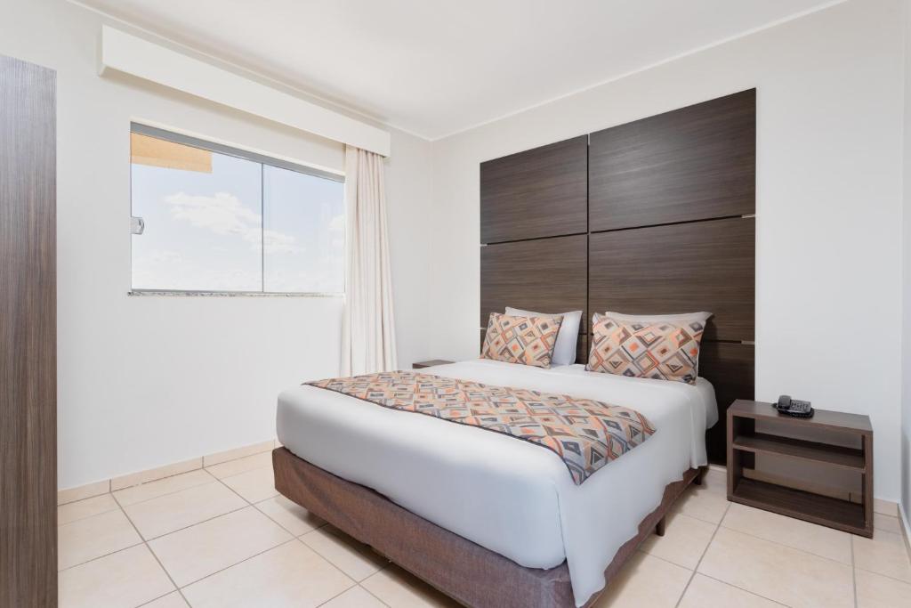 Quarto do Wyndham Olímpia Royal Hotels, com cama de casal e cabeceira de madeira escura