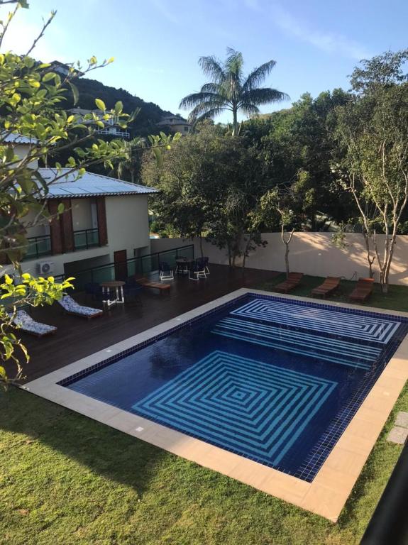 Piscina da Foca Guest House, em Búzios, cercada por árvores e espreguiçadeiras.