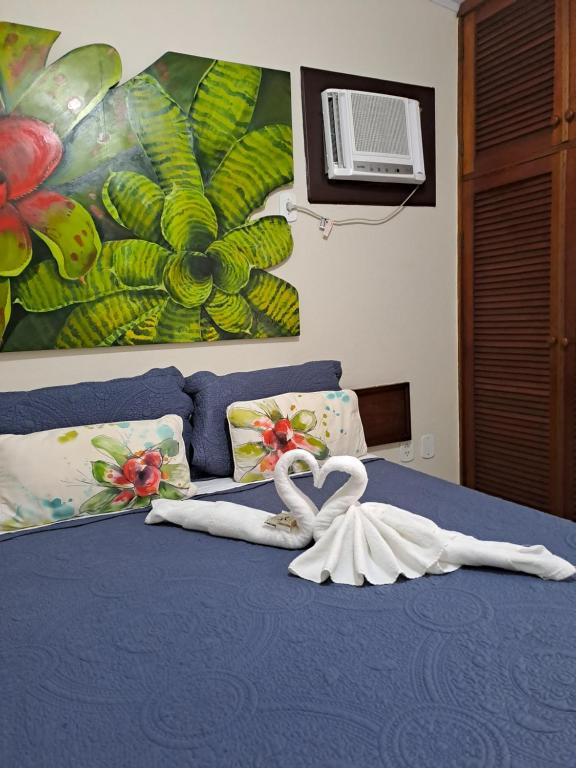Quarto da La Coloniale, em Búzios, com decoração tropical e toalhas em forma de cisnes.