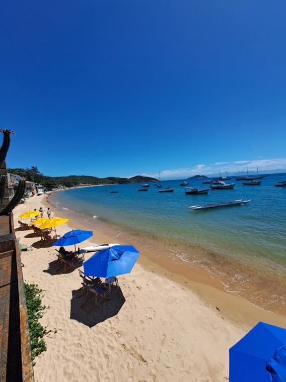 Praia em frente à La Coloniale, em Búzios, com guarda-sóis e barcos no mar.