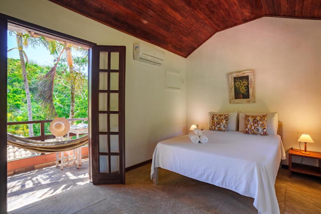 Quarto da Pousada Casa Cactus, em Búzios, com varanda e rede entre as árvores.