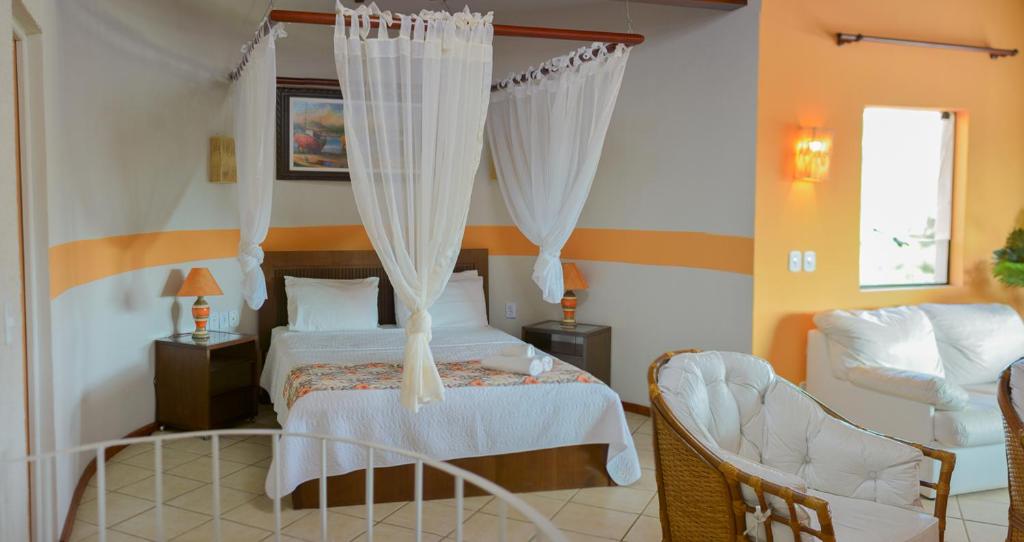 Suíte da Pousada dos Guardiões, em Búzios, com cama de dossel e sala integrada.