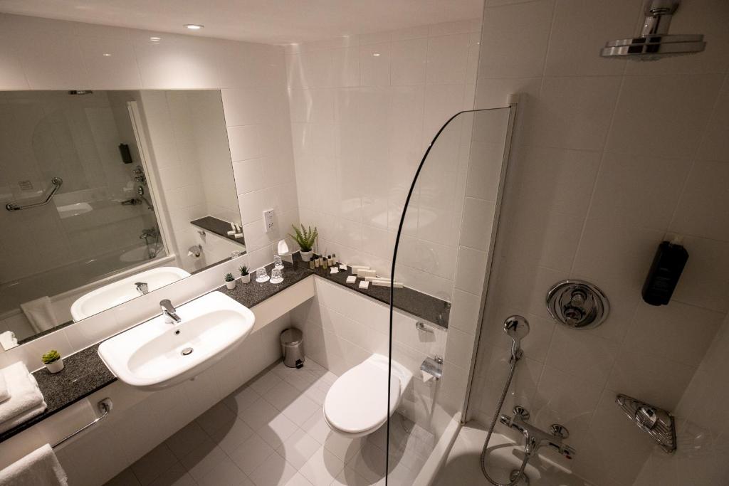 Banheiro do Maldron Hotel Smithfield Dublin City, em Dublin, com banheira e bancada ampla.