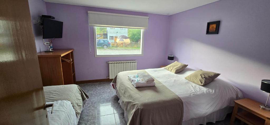 Quarto do Apart Guillaumet, em El Chaltén, com cama de casal e paredes lilás.