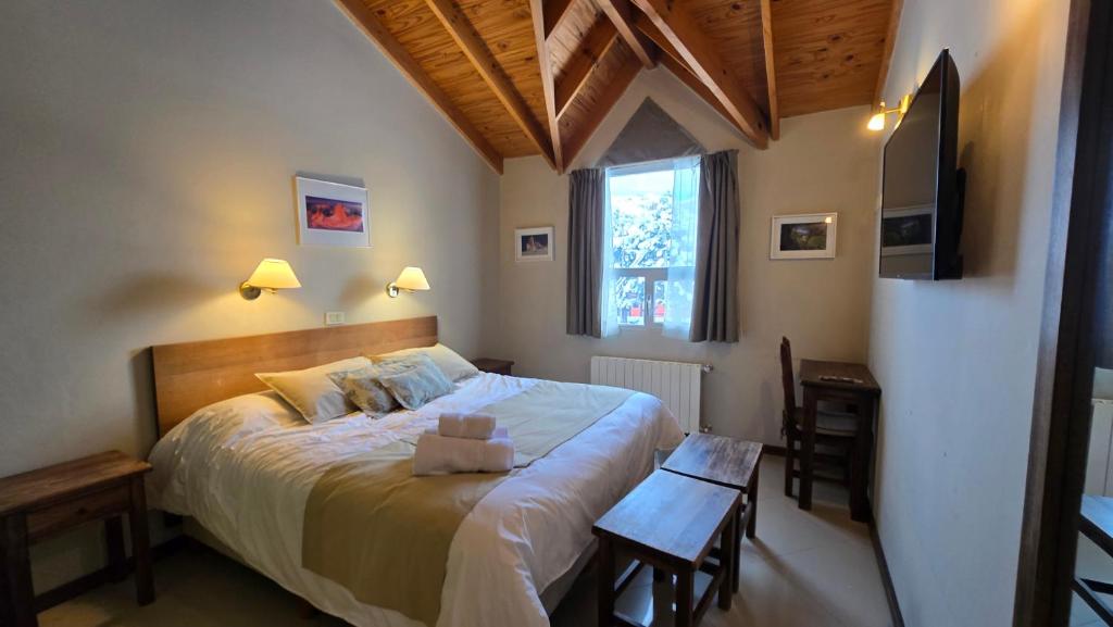 Quarto da Cumbres Nevadas Hostería Boutique, em El Chaltén, com teto de madeira e cama de casal.