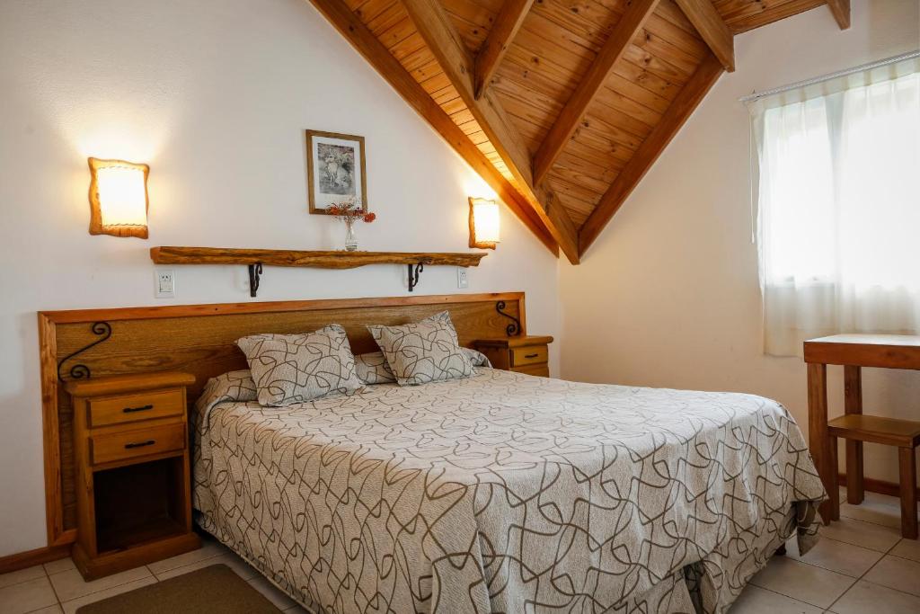 Quarto do Patagonia Hostel, em El Chaltén, com cama de casal e teto inclinado de madeira.