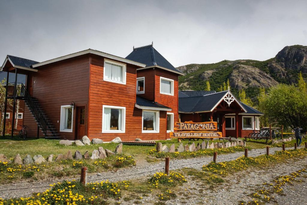 Fachada do Patagonia Hostel, em El Chaltén, com construção de madeira diante das montanhas.