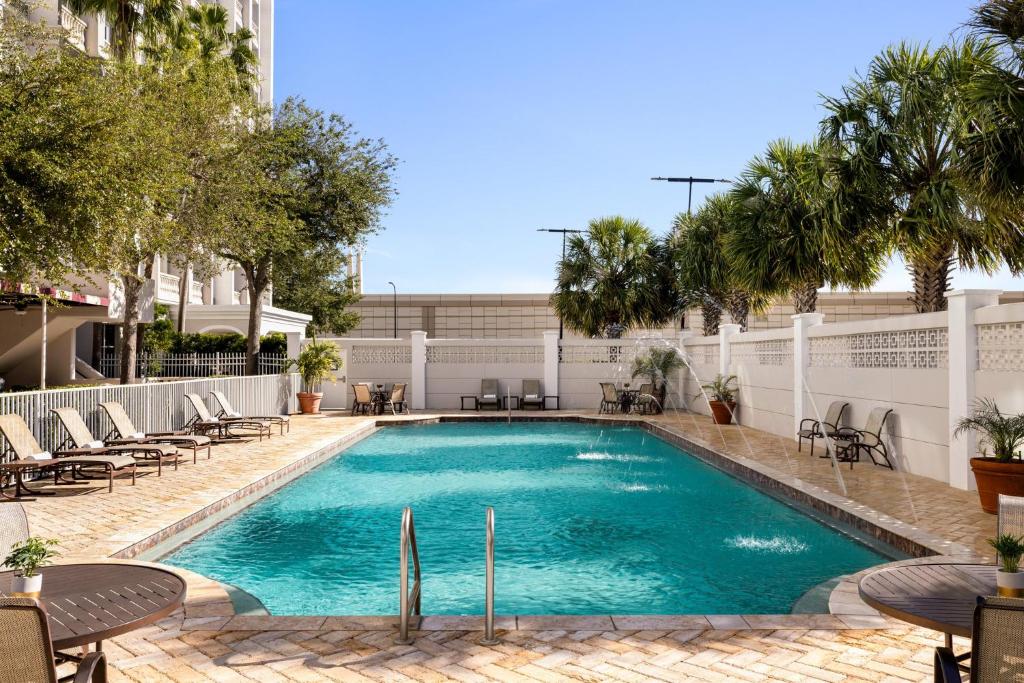 Área da piscina do Crowne Plaza Orlando Downtown, em Orlando, com espreguiçadeiras e palmeiras ao redo