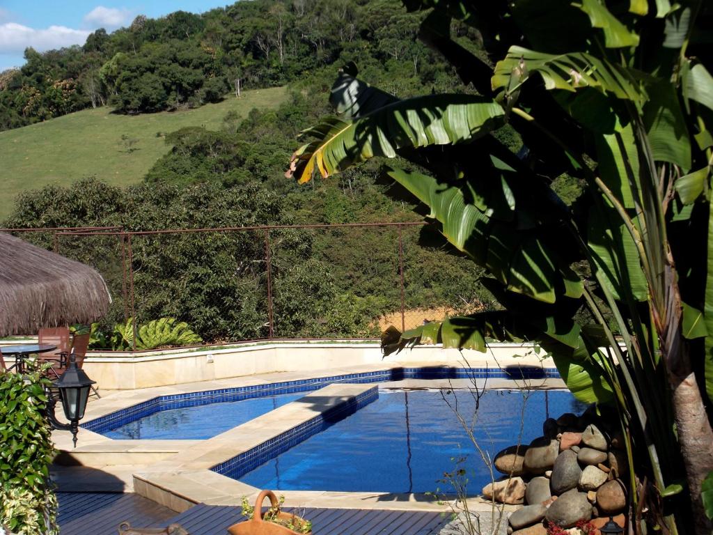 Piscinas da Casa Branca Pousada, em Pomerode, cercadas por vegetação e uma encosta verde.