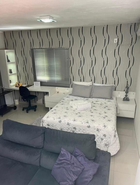 Interior do Loft com Linda Vista na Rota do Enxaimel, em Pomerode, com cama de casal, sofá e espaço de trabalho.