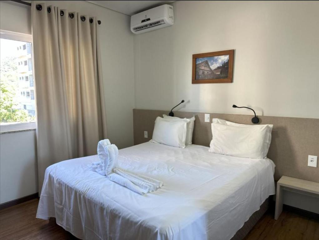 Quarto da Pousada Casarão Schmidt, em Pomerode, com cama de casal, enxoval branco e ar-condicionado.