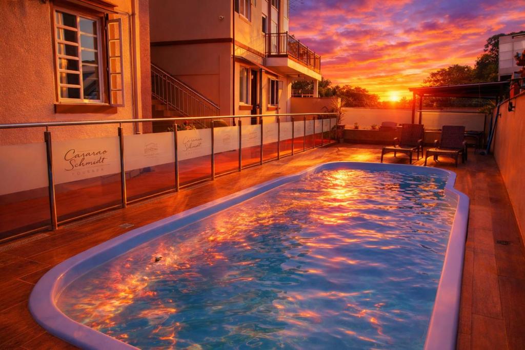 Piscina da Pousada Casarão Schmidt, em Pomerode, durante um pôr do sol alaranjado.