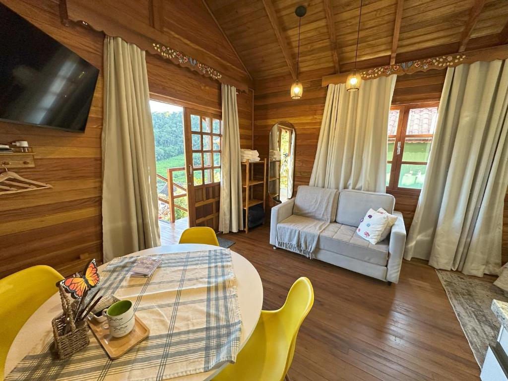 Chalé de madeira da Pousada Hoff Haus, em Pomerode, com sala de estar, mesa redonda e varanda voltada para o verde.