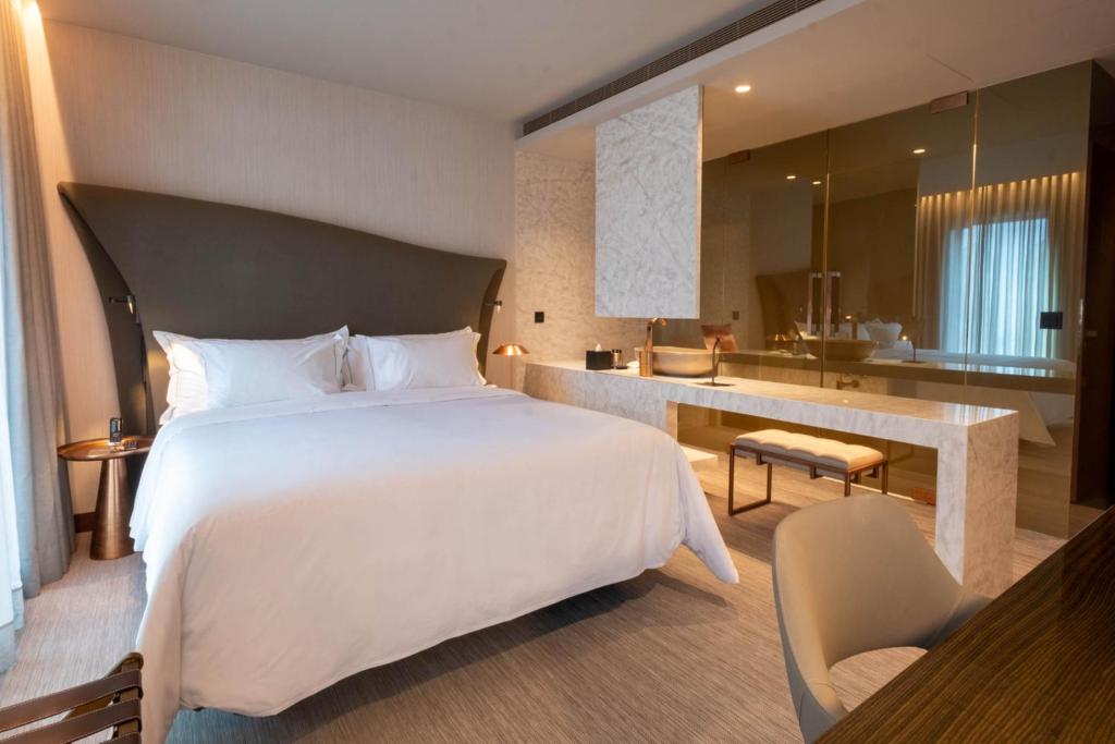 Quarto do BessaHotel Baixa, no Porto, com cama branca e banheiro integrado em mármore