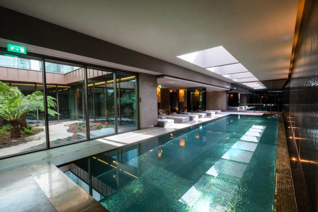 Piscina coberta do BessaHotel Baixa, no Porto, com teto de vidro e jardim interno ao lado