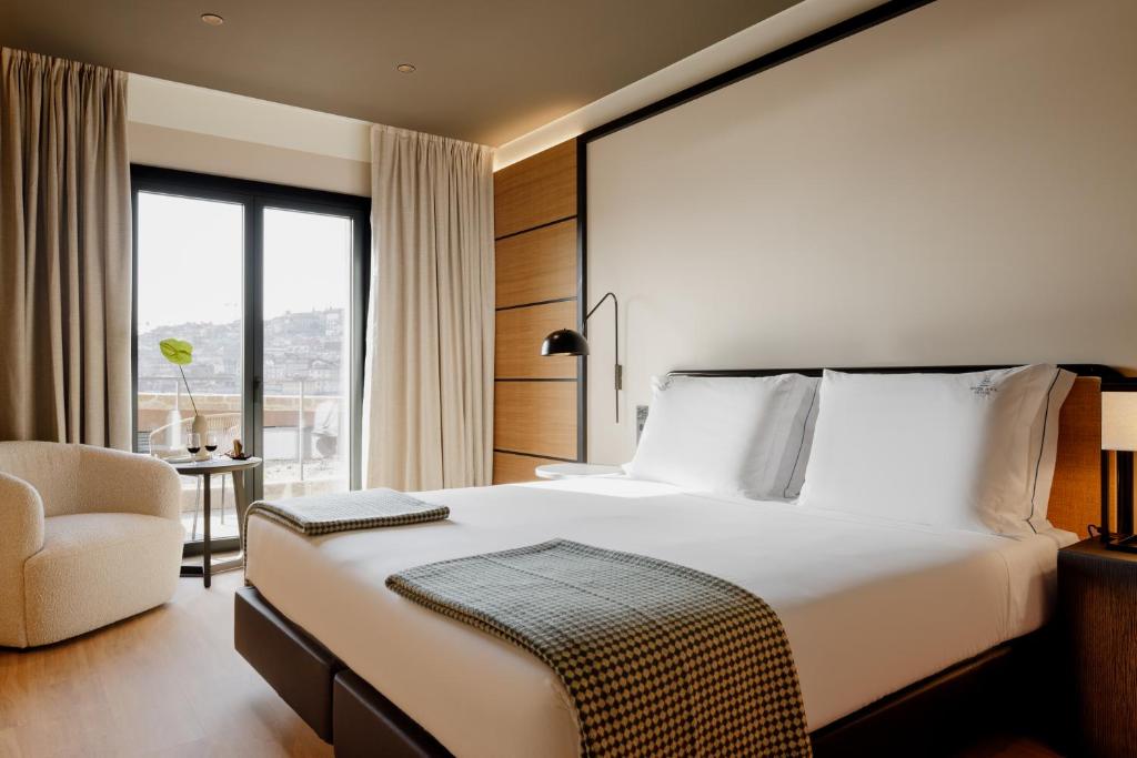 Quarto do Porto River Soul Hotel, no Porto, com cama branca, poltrona clara e janela para a cidade