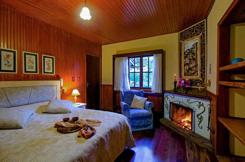 Quarto do Hotel Bühler, em Visconde de Mauá, com cama de casal e lareira acesa