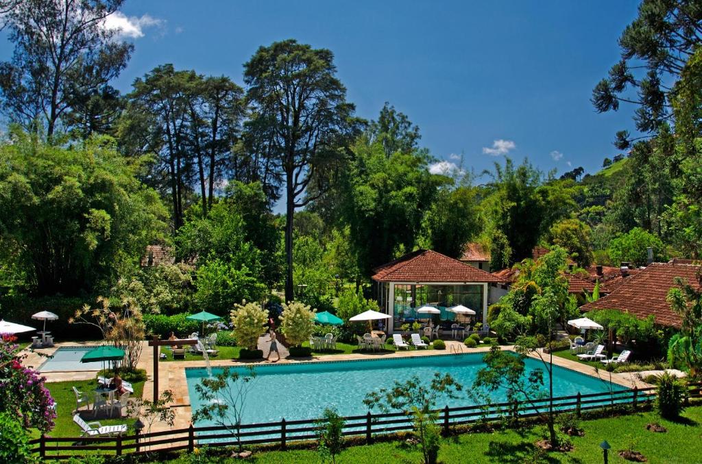 Área externa do Hotel Bühler, em Visconde de Mauá, com piscina cercada por jardins e árvores altas