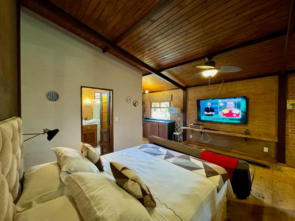 Quarto da Pousada Chalés Jardim das Bromélias, em Visconde de Mauá, com cama e teto de madeira