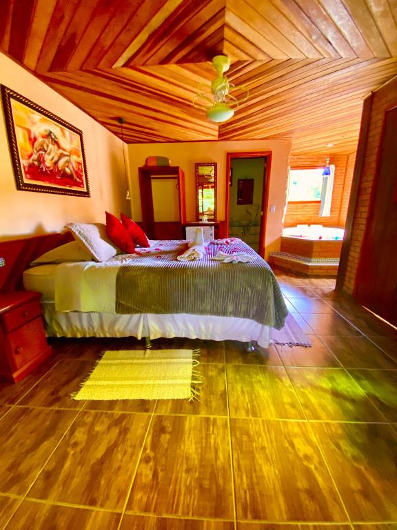 Quarto da Pousada Magia da Montanha, em Visconde de Mauá, com cama de casal e banheira ao fundo