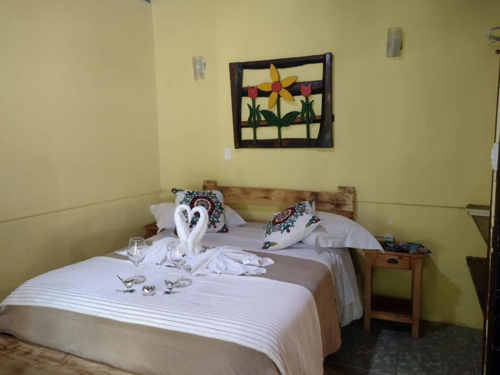 Quarto da Pousada Toque de Minas, em Visconde de Mauá, com cama de casal e decoração floral na parede