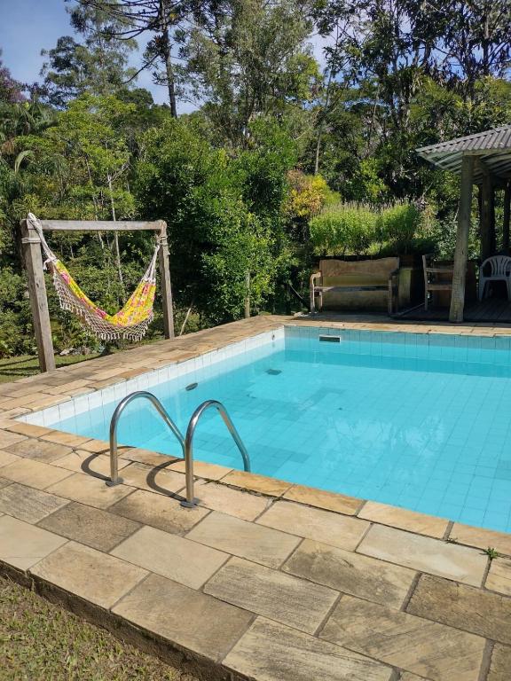 Piscina da Pousada Toque de Minas, em Visconde de Mauá, com rede e jardim ao redor