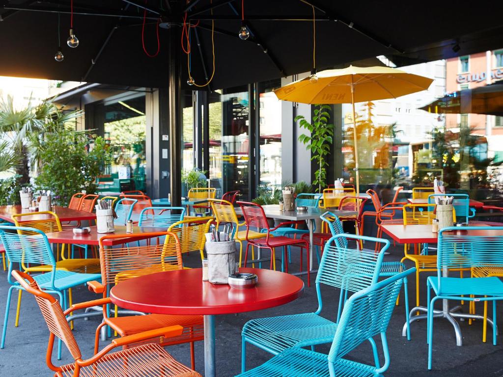 Terraço do 25hours Hotel Langstrasse, em Zurique, com mesas coloridas.