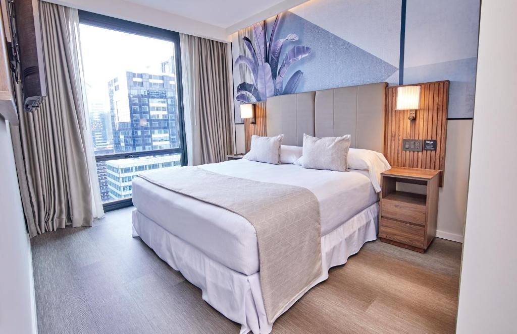 Quarto do Riu Plaza Manhattan Times Square, em Nova York, com cama de casal e janelão para a cidade.