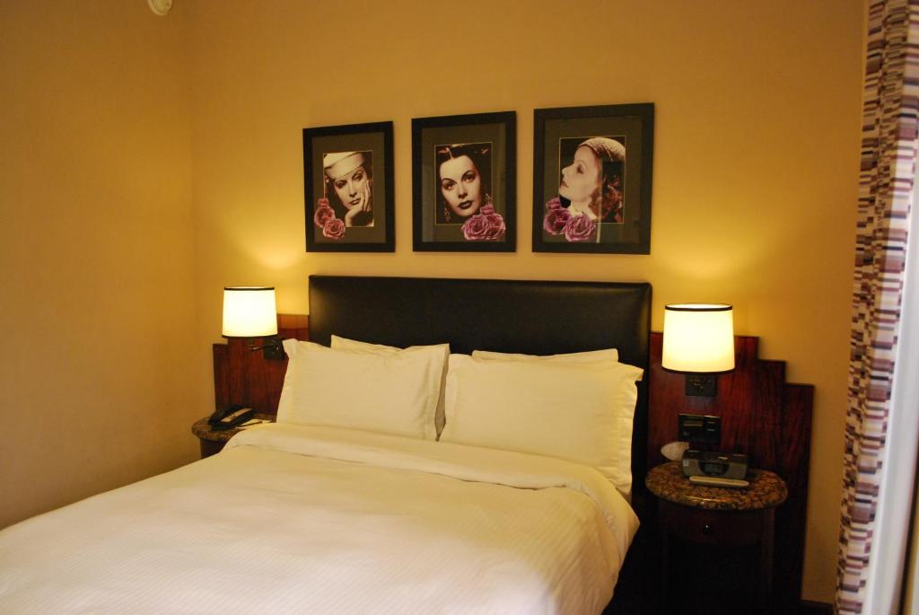 Quarto do Washington Square Hotel, em Nova York, com cama de casal e retratos na parede.