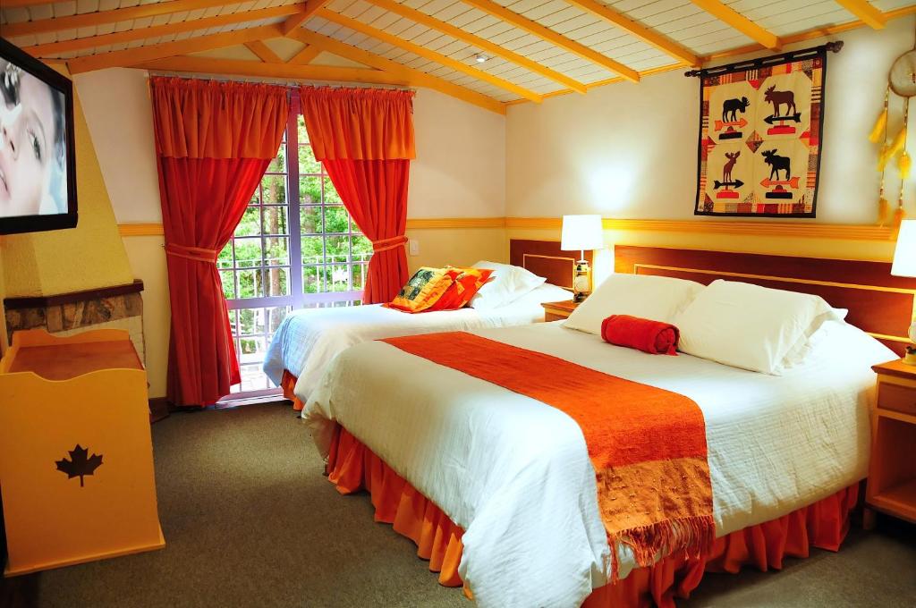 Quarto da Canada Lodge, em Campos do Jordão, com duas camas e decoração em tons de laranja