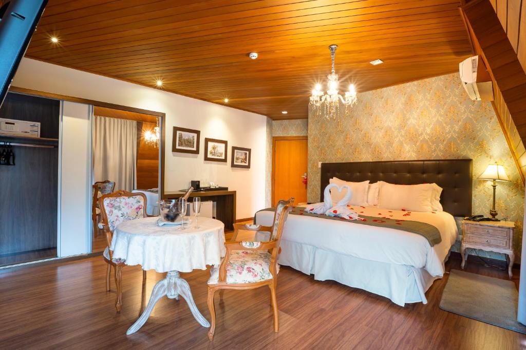 Quarto da Pousada Luis XV, com cama de casal, mesa redonda e lustre