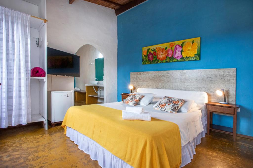 Quarto da Pousada Recanto da Villa, com parede azul e cama com manta amarela