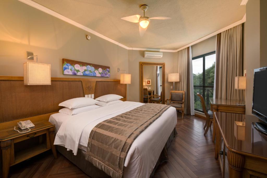Quarto do Wish Serrano Resort, em Gramado, com cama de casal, varanda e móveis em madeira